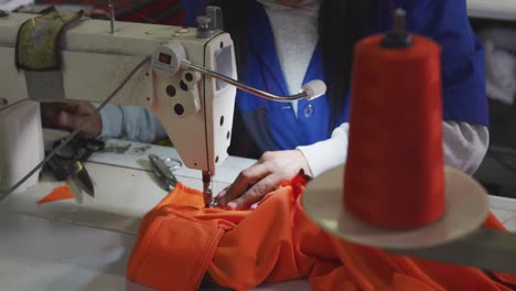 Mixed-race-woman-using-sewing-machine-in-factory