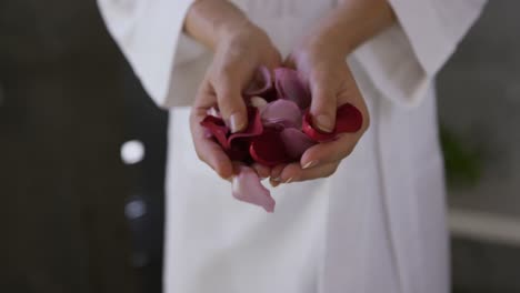 Caucasian-woman-holding-rose-petals-in-hotel
