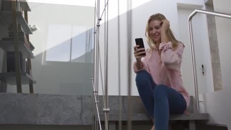 Caucasian-woman-smiling-at-her-smartphone-in-hotel