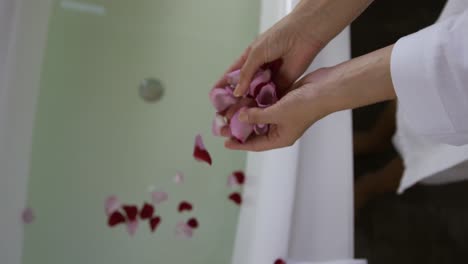 Caucasian-woman-putting-rose-petals-in-bath-tub-in-hotel
