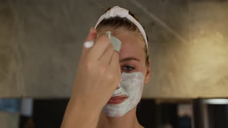 Caucasian-woman-putting-on-face-mask-in-hotel