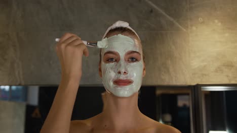 Caucasian-woman-putting-on-face-mask-in-hotel