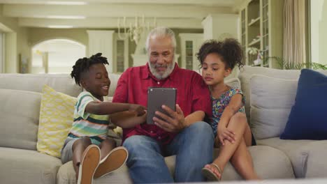 Grandfather-and-grandchildren-using-digital-tablet-at-home
