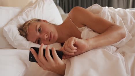 Caucasian-woman-resting-in-bed-in-hotel-room