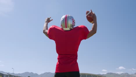American-football-player-standing-with-arms-raised