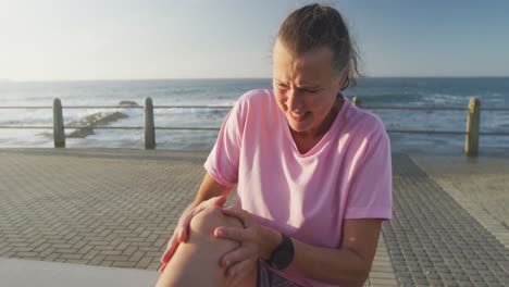 Senior-woman-in-pain-holding-her-leg-on-a-promenade