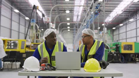 Warehouse-workers-using-laptop-in-factory