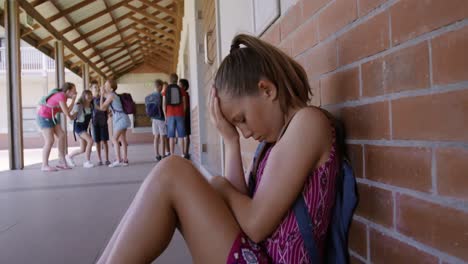 Trauriges-Mädchen-Mit-Der-Hand-Auf-Dem-Kopf,-Das-Im-Schulkorridor-Sitzt