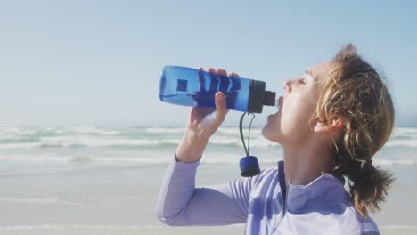 Mujer-Atlética-Bebiendo-Agua-En-La-Playa