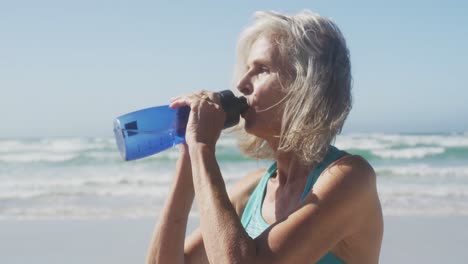 Ältere-Frau-Trinkt-Wasser-Am-Strand