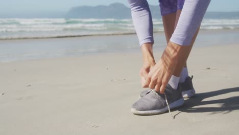 Mujer-Atlética-Atando-Sus-Zapatos-En-La-Playa