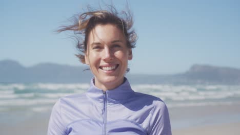 Athletische-Frau-Lächelt-Und-Blickt-In-Die-Kamera-Am-Strand