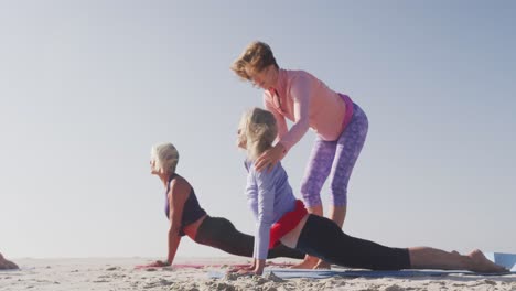 Yogalehrer-Unterrichtet-ältere-Frauen-Am-Strand-In-Yoga
