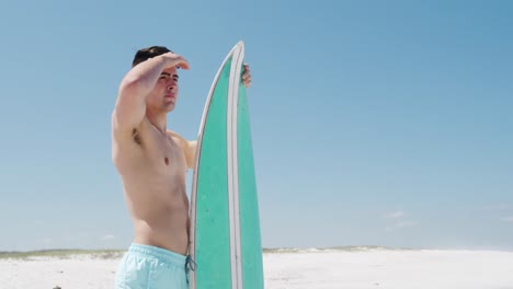 Man-holding-a-surfboard-on-the-beach