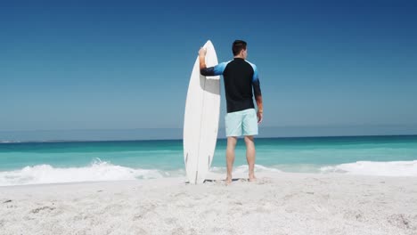 Hombre-Sujetando-Una-Tabla-De-Surf-En-La-Playa