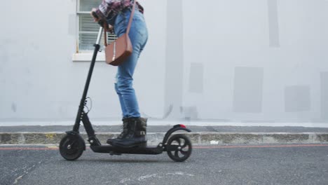 Mixed-race-woman-using-electric-scooter