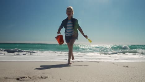 Young-girl-running-at-the-beach-with-toys
