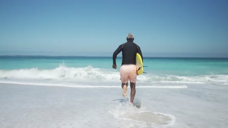 Senior-man-running-to-the-ocean-with-a-surfboard