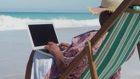Senior-woman-using-laptop-at-the-beach