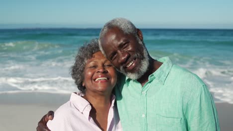 Senior-couple-looking-at-the-camera-at-the-beach