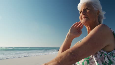 Senior-woman-sitting-looking-away-at-the-beach