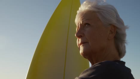 Senior-woman-with-a-surfboard-at-the-beach