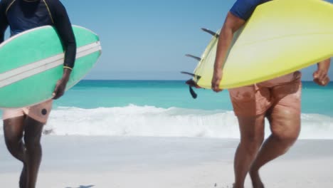 Senior-couple-running-with-surfboards