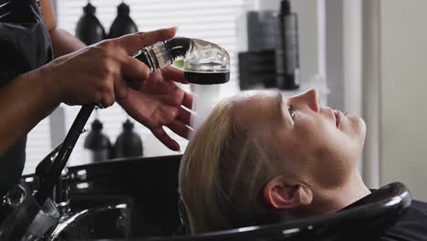 Side-view-woman-having-her-hair-washed-by-a-hairdresser