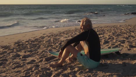 Senior-man-sitting-on-the-sand-at-the-beach
