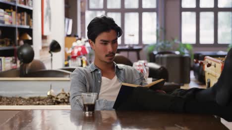 Mixed-race-man-reading-book-in-his-apartment