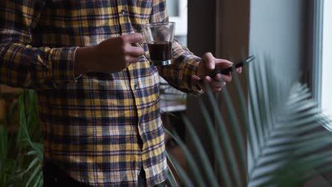 Mann-Mit-Gemischter-Abstammung,-Der-Kaffee-Trinkt-Und-Sein-Telefon-Benutzt