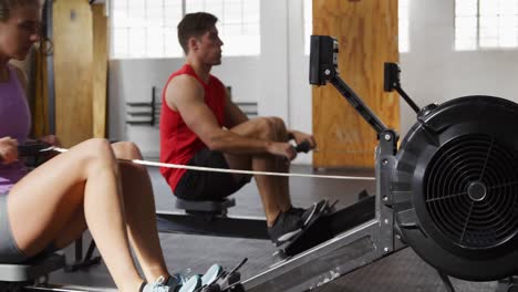 Side-view-athletic-Caucasian-friends-exercising-on-a-rowing-machine