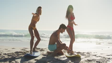 Caucasian-friends-training-surf-styling-on-the-sand-