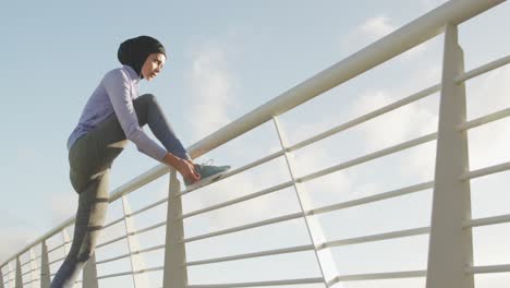 Frau-Trägt-Hijab,-Hört-Draußen-Musik-Und-Bindet-Ihre-Schnürsenkel