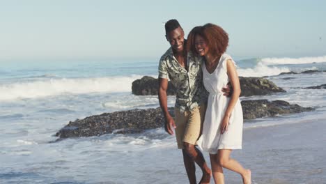 African-American-couple-walking-seaside-and-kissing
