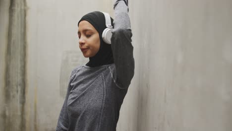 Mujer-Exhausta-En-Ropa-Deportiva-Con-Auriculares-Inalámbricos-Usando-Hijab
