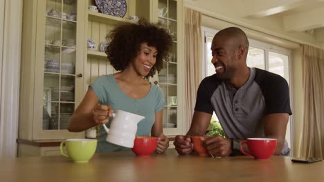 Happy-mixed-race-couple-eating-breakfast-in-their-kitchen