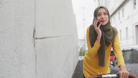 Mujer-Con-Hijab-Teniendo-Una-Llamada-Telefónica-En-Bicicleta