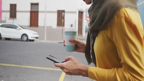 Mid-section-view-of-a-woman-wearing-hijab-and-using-her-phone