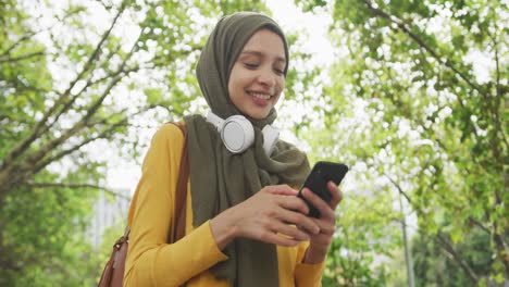 Frau-Trägt-Hijab-Mit-Kabellosen-Kopfhörern-Und-Benutzt-Ihr-Telefon