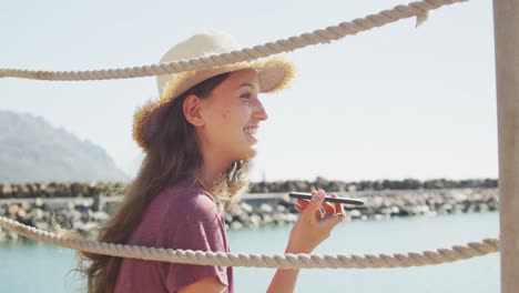 Side-view-of-a-teenage-Caucasian-girl-having-a-phone-call-harbor-side