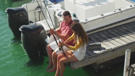 Side-view-of-a-Caucasian-man-and-his-teenage-daughter-fishing-harbor-side-