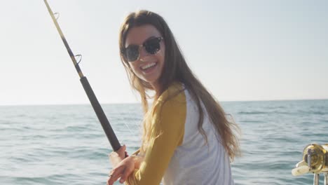 Side-view-of-a-teenage-Caucasian-girl-fishing-on-boat-and-looking-at-camera
