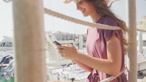 Side-view-of-a-teenage-Caucasian-girl-using-her-phone-harbor-side