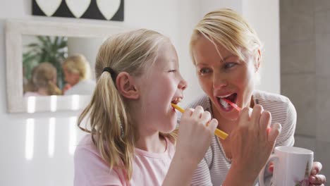 Side-view-of-Caucasian-woman-and-her-daughter-brushing-their-teeth