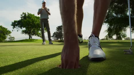 Golfista-Caucásico-Alcanzando-Una-Pelota-Fuera-Del-Hoyo-En-Un-Campo-De-Golf-En-Un-Día-Soleado