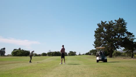 Caucasian-male-golfers-playing-on-a-golf-course-on-a-sunny-day