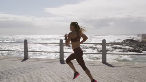 Sporty-Caucasian-woman-exercising-on-a-promenade-on-seaside