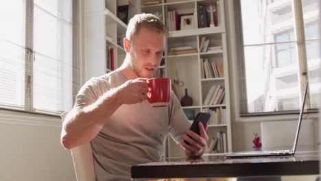 Caucasian-male-in-social-distancing-drinking-coffee-at-home