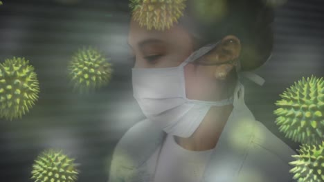 Animation-Von-Makro-Coronavirus-Covid-19-Zellen,-Die-Sich-über-Eine-Asiatische-Frau-Mit-Gesichtsmaske-Ausbreiten